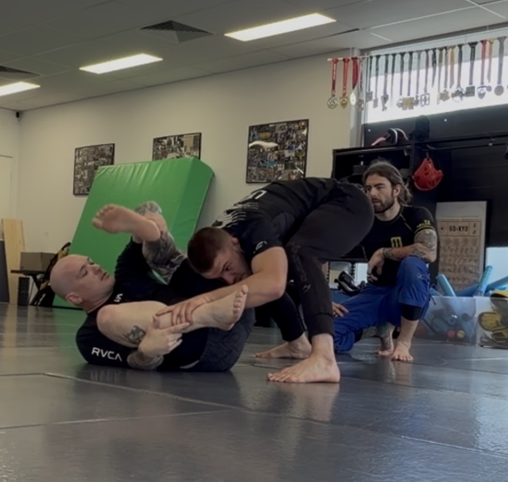 Two students working a leg entanglement in a no-gi round at Mat Shark