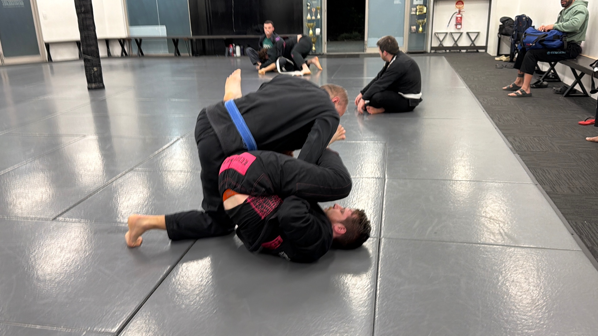 Two students rolling in the gi during an adults class at Mat Shark