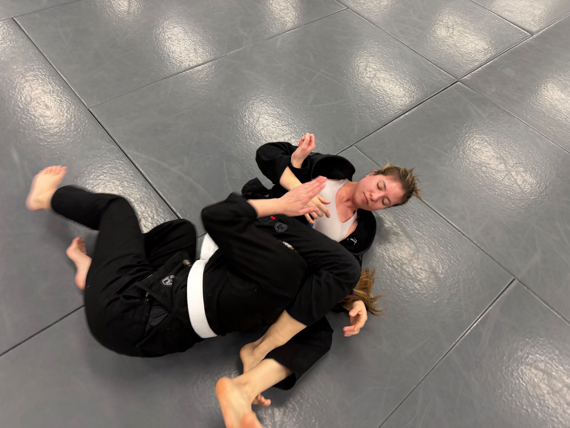 Two students rolling in the gi during an adults class at Mat Shark