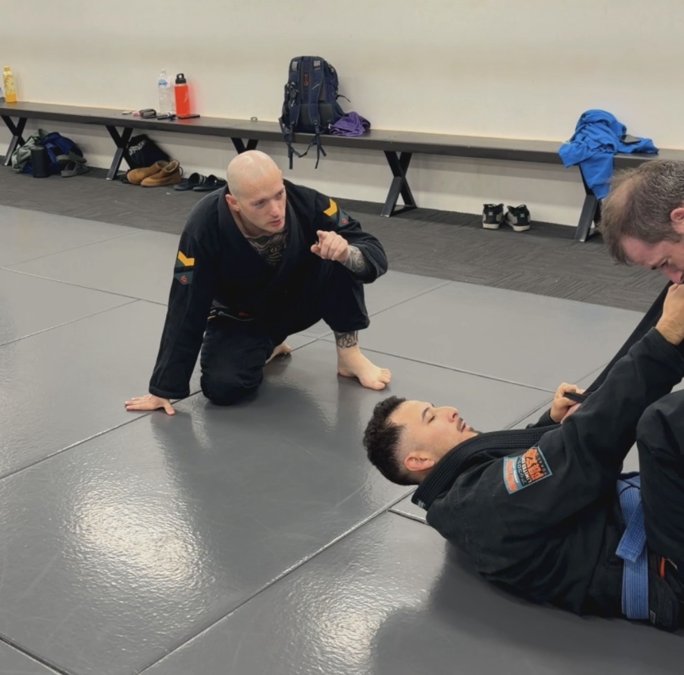 A coach talking a student through a position on the mats