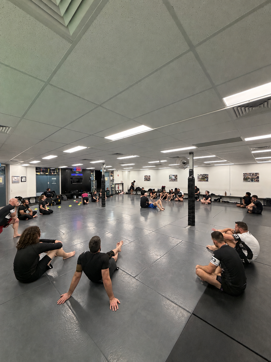 An adults class sitting in a circle on the mats at Mat Shark