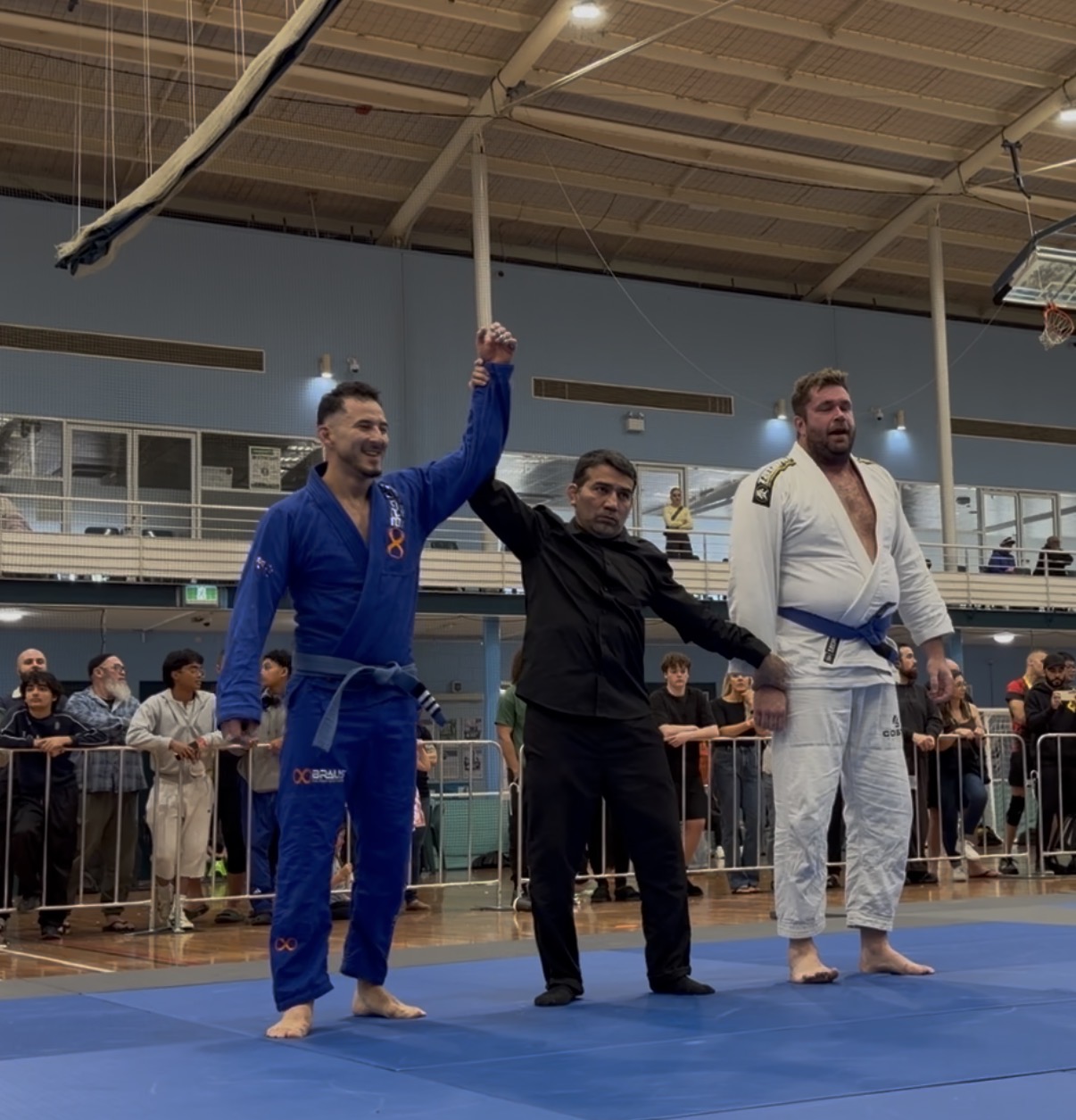 A Mat Shark blue belt having his hand raised after winning a gi match