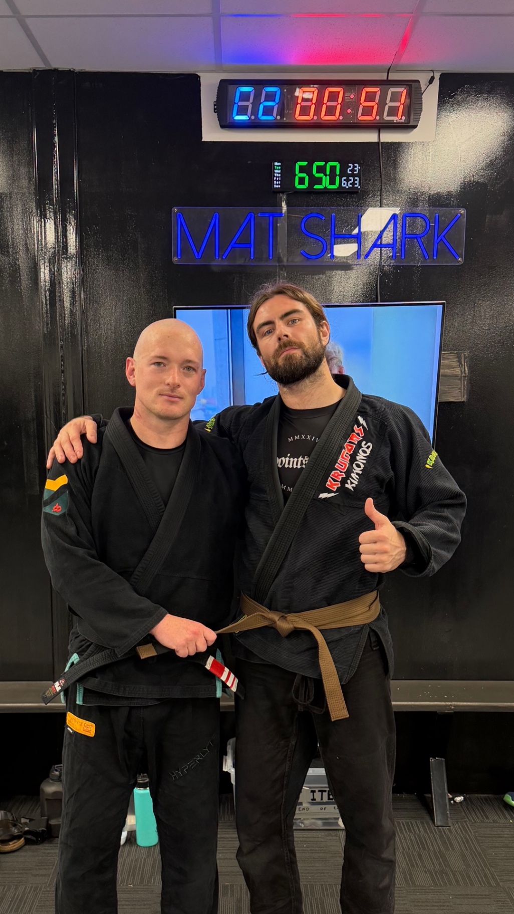 Mat Shark coaches together under the academy neon sign