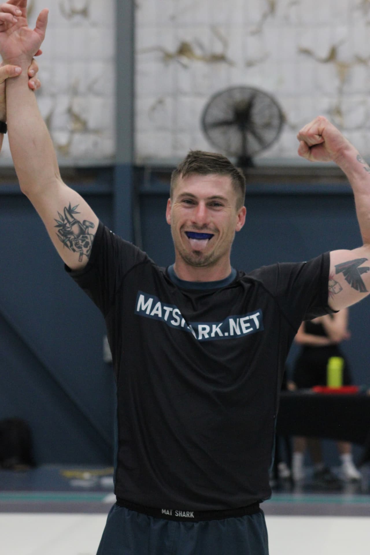 A Mat Shark athlete celebrating a win with his hand raised