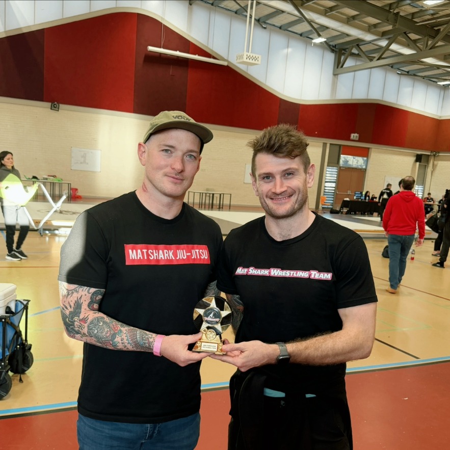 Mat Shark coaches with the wrestling team trophy