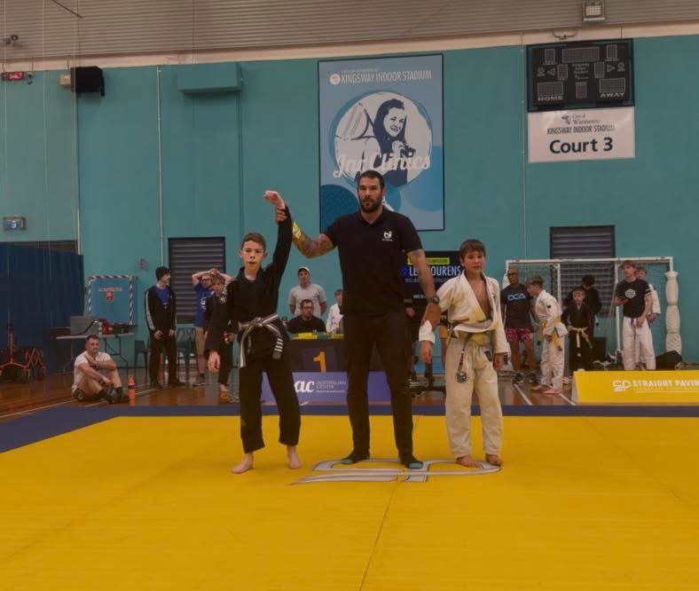 A Mat Shark kid getting his hand raised at a competition