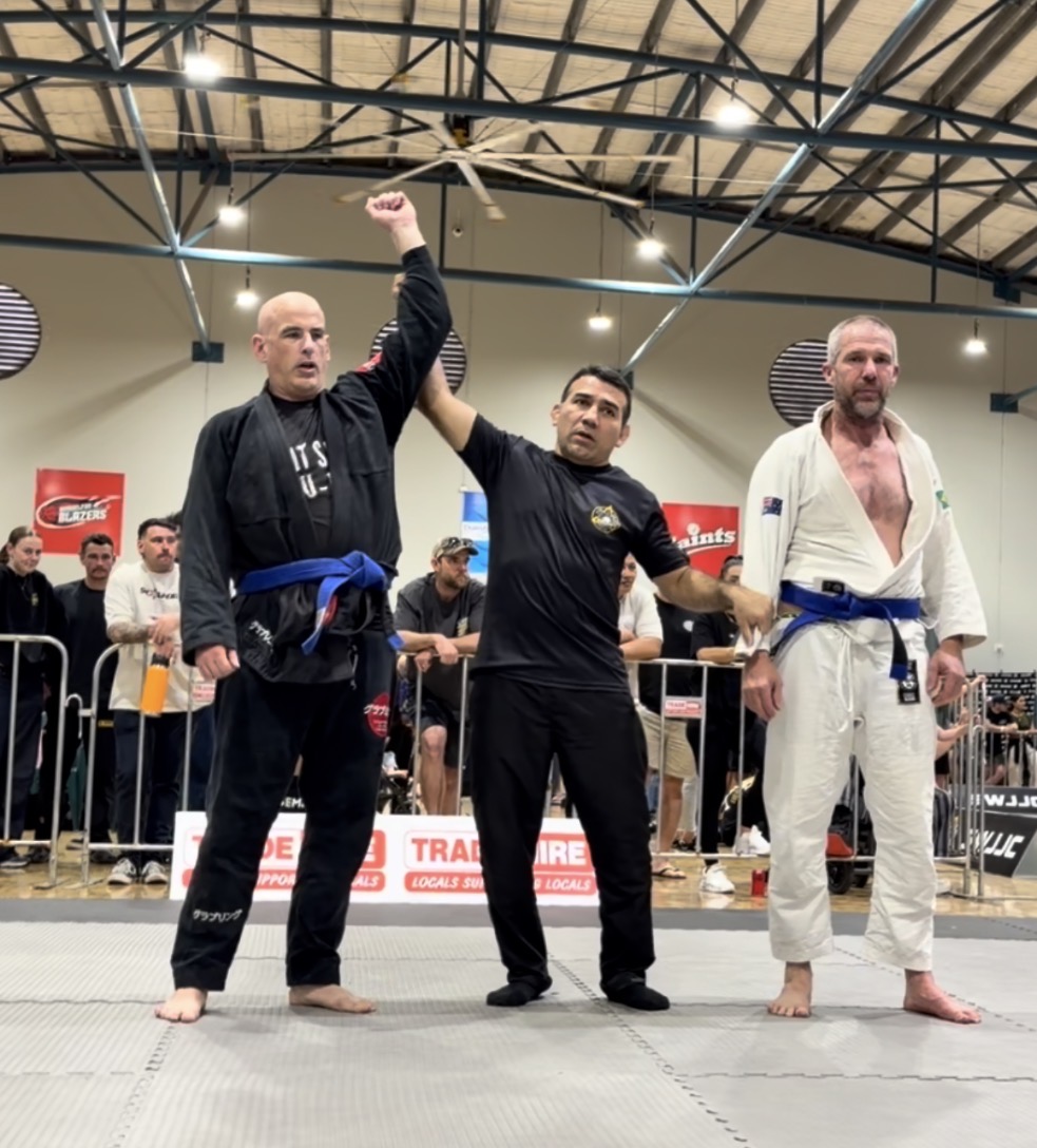 A Mat Shark competitor having his arm raised by the referee after a gi match