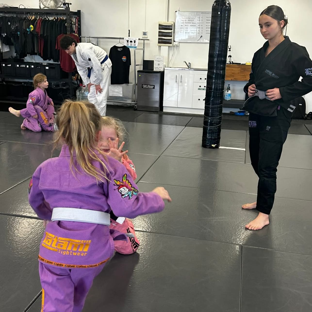 Young children practising a drill with a coach nearby