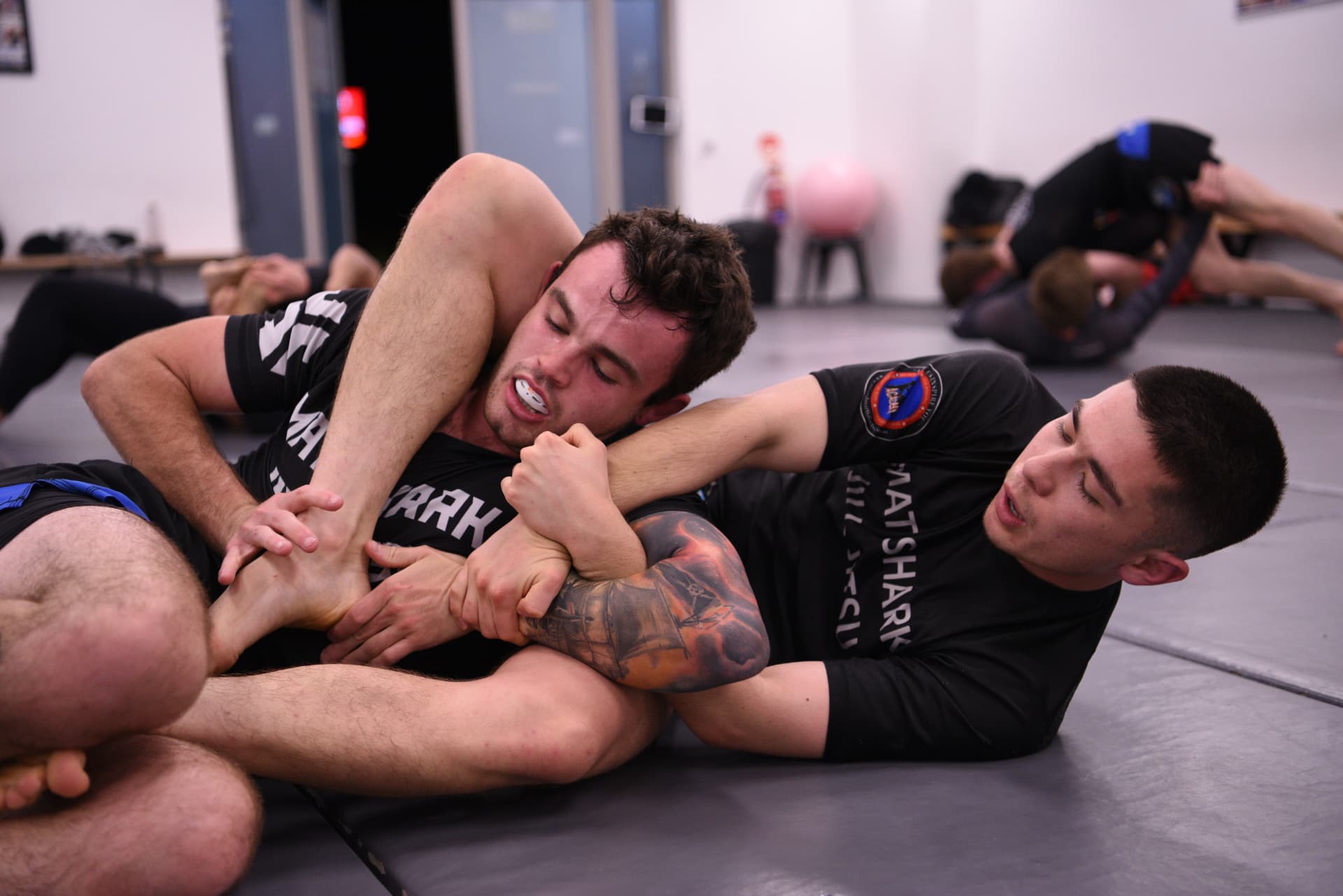 Two students rolling in a no-gi class at Mat Shark
