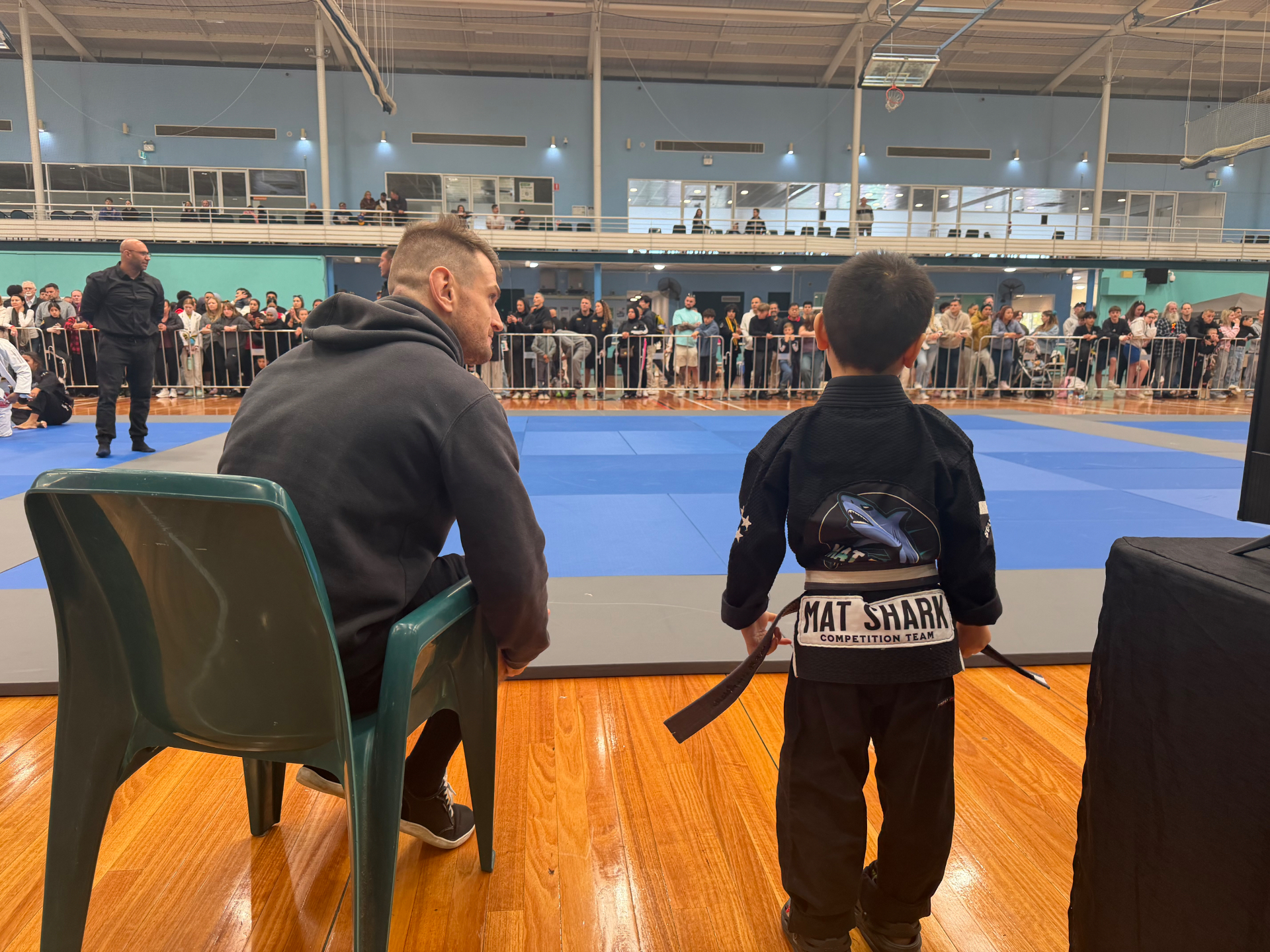 A Mat Shark coach matside with a young competitor before his match
