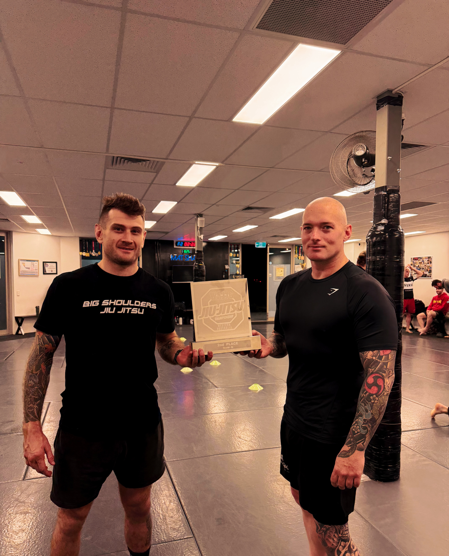 Two Mat Shark coaches holding the WAJJC second place masters gi trophy