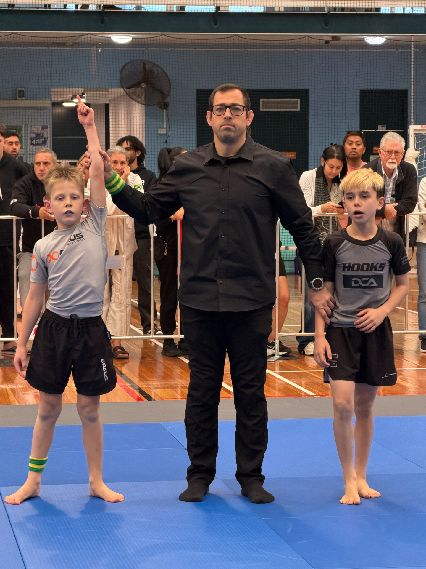 A Mat Shark kid having his hand raised by the referee after a win